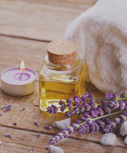 A Comforting Candle Next To A Towel And Lavender, All A Part Of Twin Pine Manor'S Spa Package.